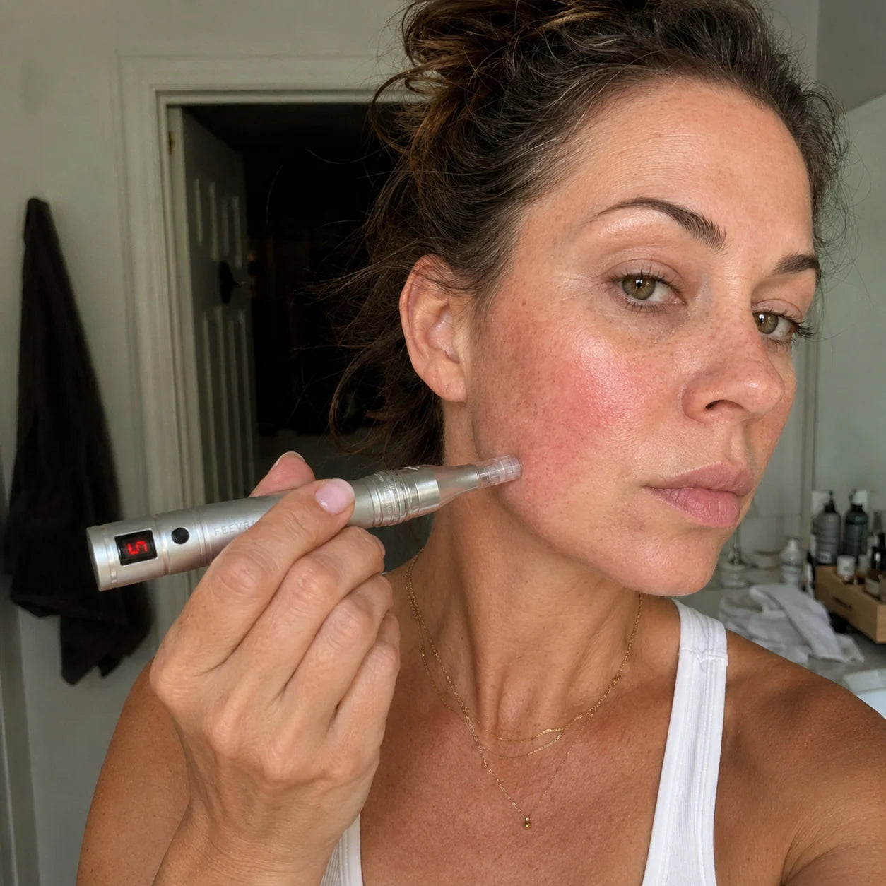 Kvinde fører Feevra Microneedling Dermapen langs kæben