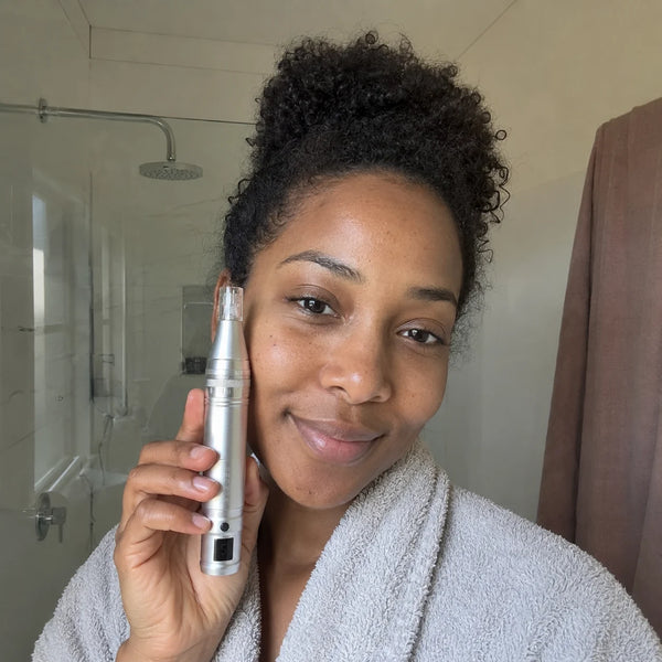 Kvinde med krøllet hår bruger Feevra Microneedling Dermapen på kinden