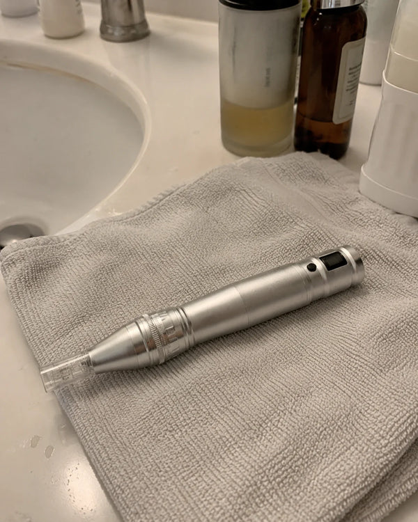 Feevra Microneedling Dermapen ligger på håndklæde ved håndvasken